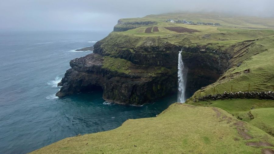 Faroe islands waterfall in the distance against the ocean