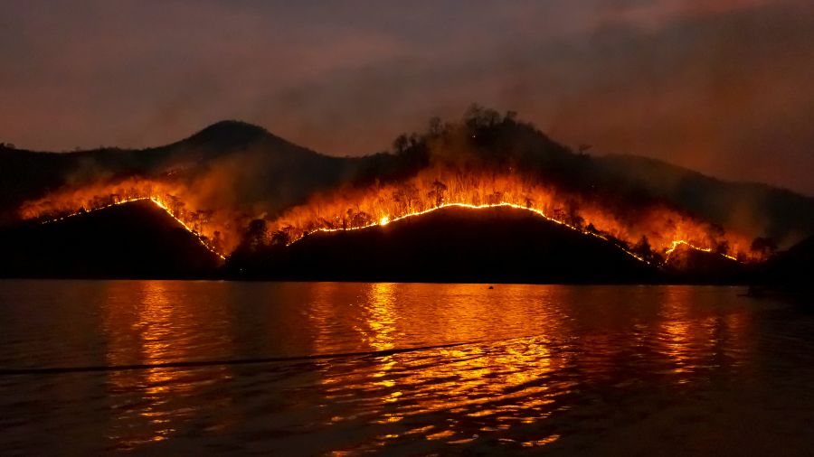 a wildfire lights up the night sky over a lake