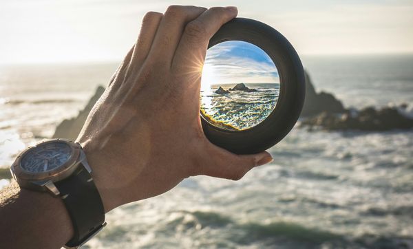 hand holds glass ball against ocean backdrop hand holds glass ball against ocean backdrop